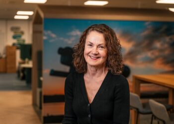 Smiling woman in office with colourful background.