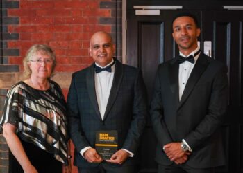 Three people at an awards ceremony in formal attire.