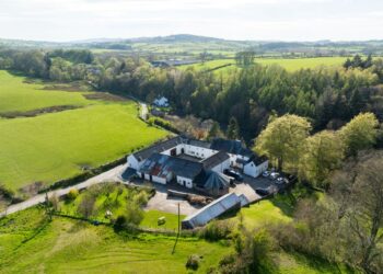 Aerial view of countryside farm and buildings in lush greenery.