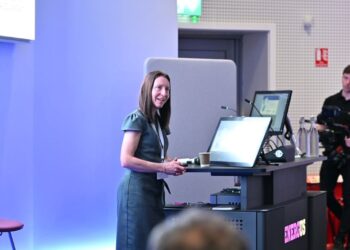 Woman presenting at a business conference with a screen.
