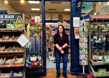 Pet shop with employee, snacks and supplies on display.