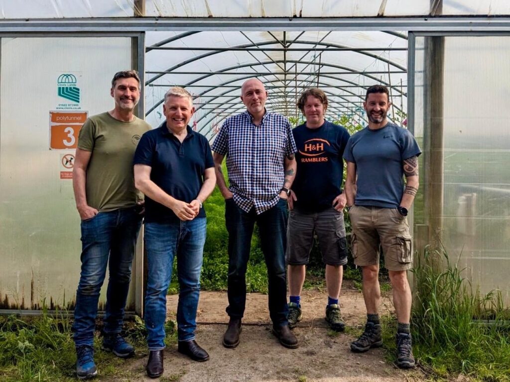 Five men standing in a greenhouse.