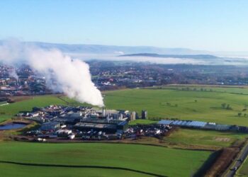 Aerial view of a countryside factory emitting steam.