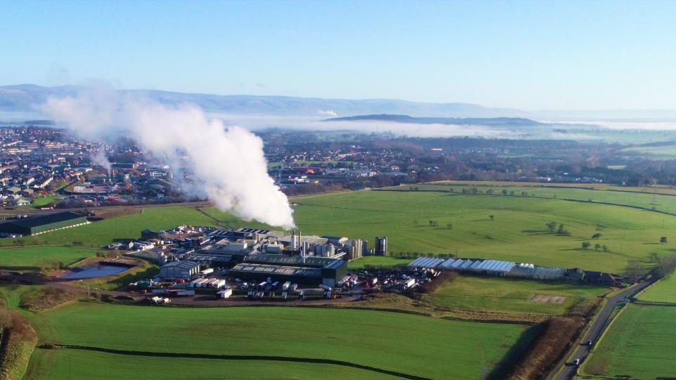 Aerial view of a countryside factory emitting steam.