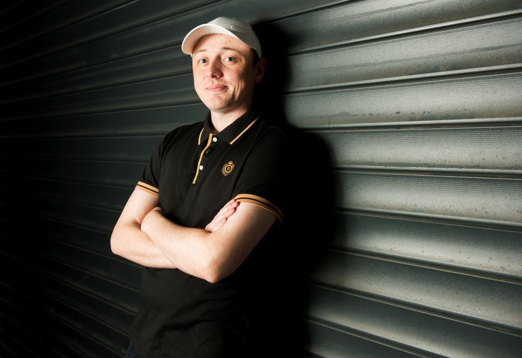 Person in black shirt and white cap, arms crossed, smiling.