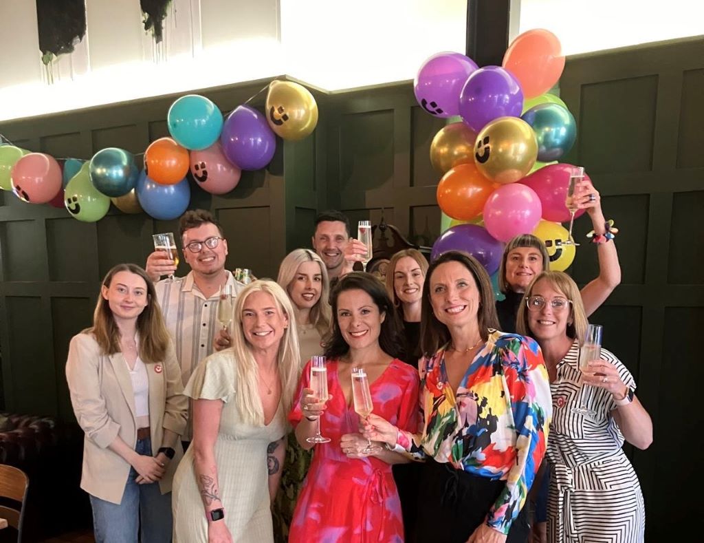 Group celebrating with balloons and champagne.