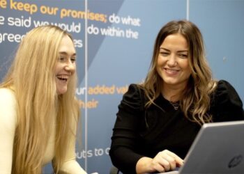 Two women smiling at a laptop.