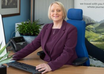 Woman in office at desk, smiling.