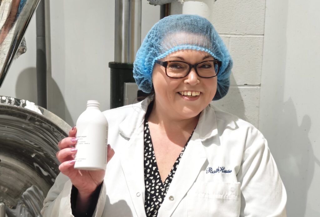 Smiling worker holding product in manufacturing facility.