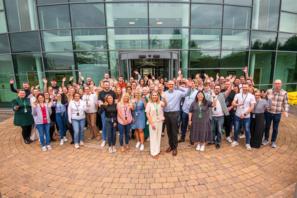 Group photo of office staff outside building.