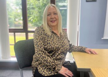 Woman in leopard print shirt sitting at desk.