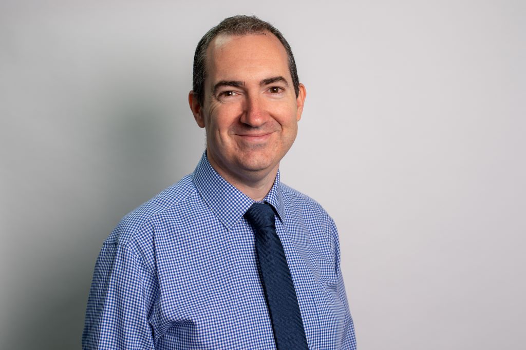 Smiling man in blue checkered shirt and tie