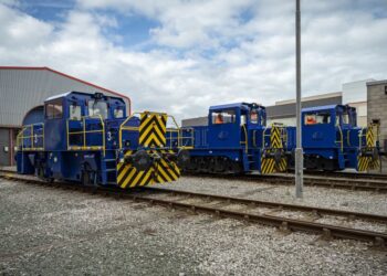 Blue diesel locomotives parked outside a warehouse