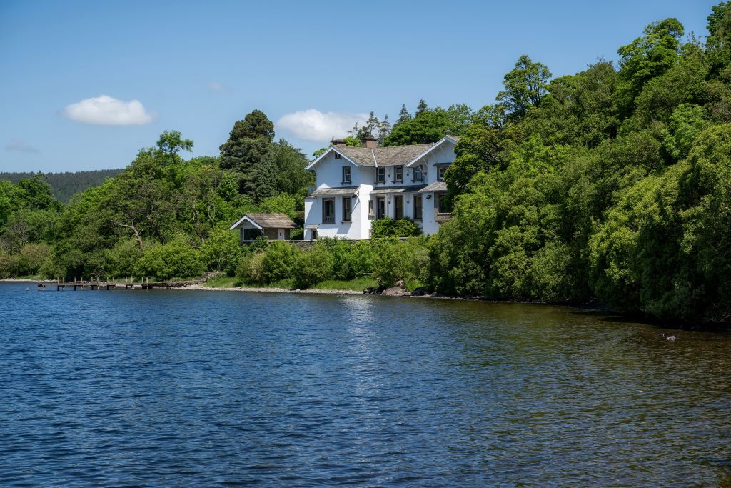 White house by lake surrounded by trees