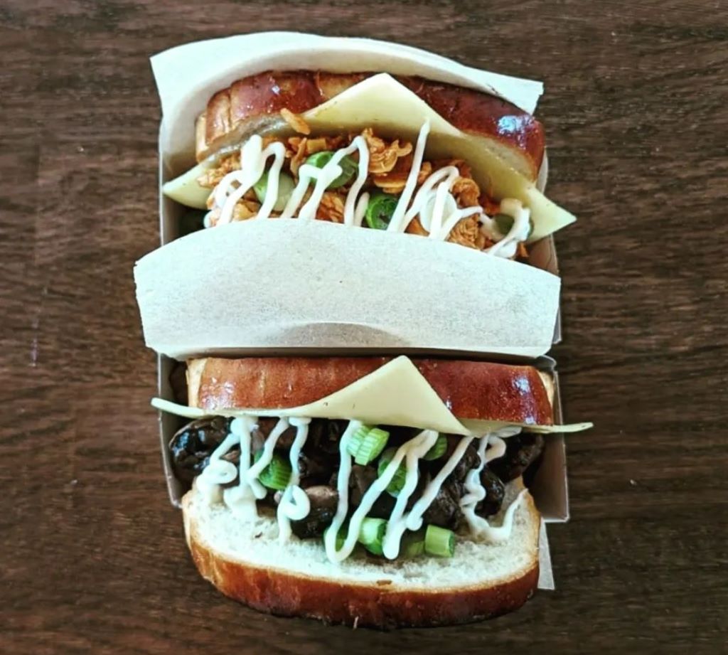 Two filled sandwiches with meat and toppings.