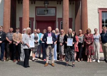 Group photo of people holding certificates outside building.