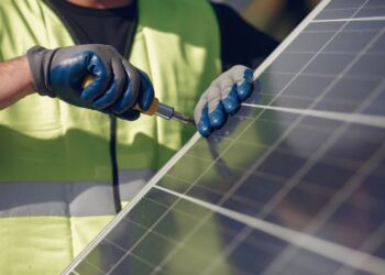 Technician installing solar panels outdoors.