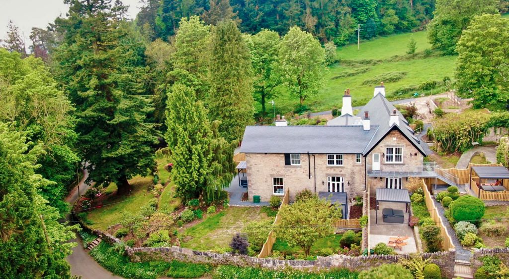 Aerial view of countryside house surrounded by trees.