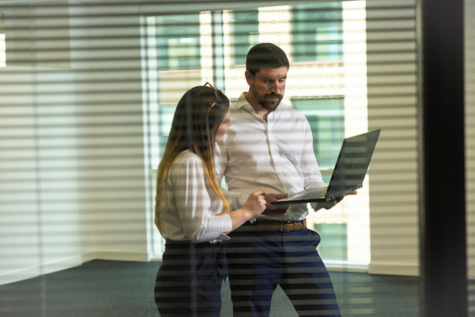 Two colleagues collaborating on a laptop computer.