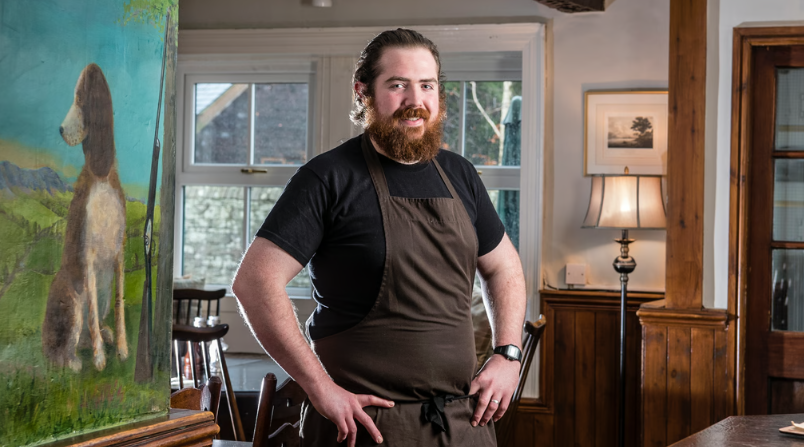 Smiling man in apron standing in a cosy pub.