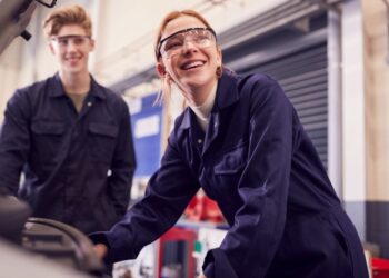 Two mechanics smiling and working in a workshop