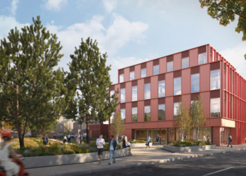 Modern red office building with trees and pedestrians.