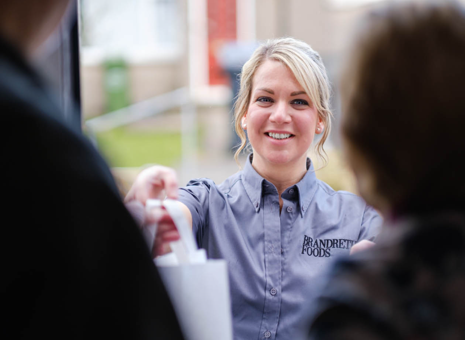Smiling female food delivery worker handing bag