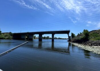 Bridge over calm river on sunny day.