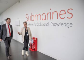 People walking past Submarines Academy sign.