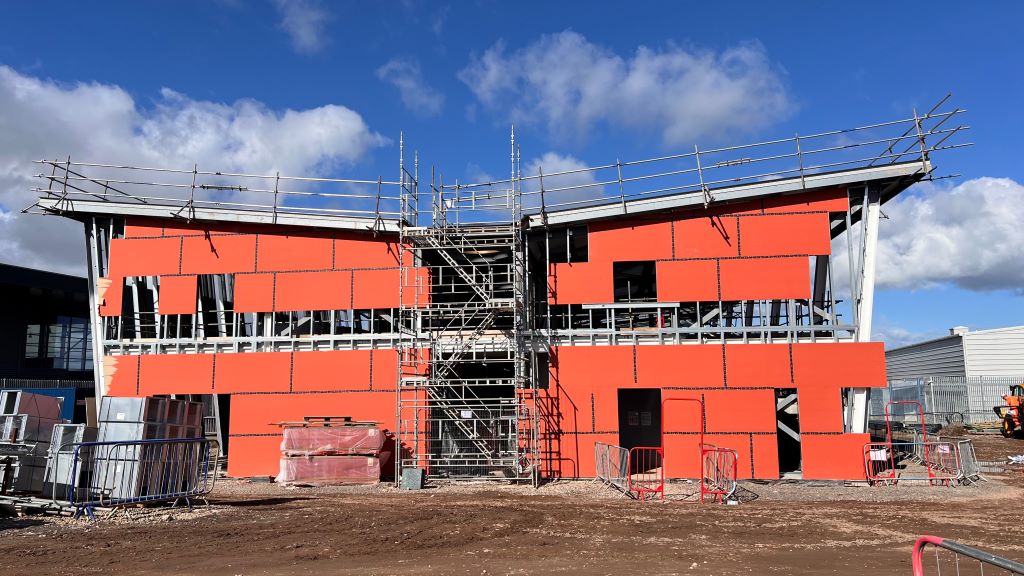 Modern building under construction with orange panels