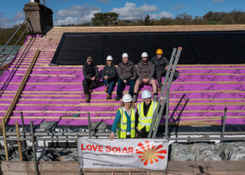 Workers installing solar panels on a roof