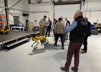 Group gathered around a robotic dog demonstration.