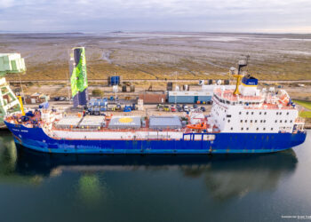 Cargo ship with wind propulsion near dockyard