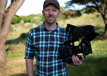 Man holding camera in scenic outdoor setting.