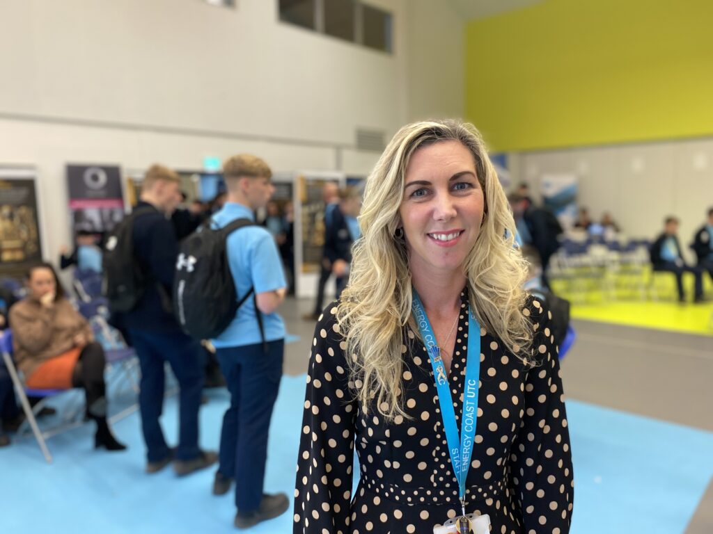 Woman smiling at educational event with students.