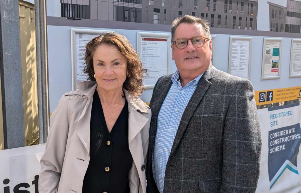 Man and woman at construction site display board.