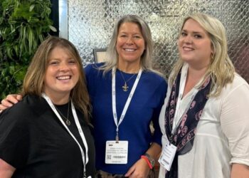 Three smiling women at a professional event.