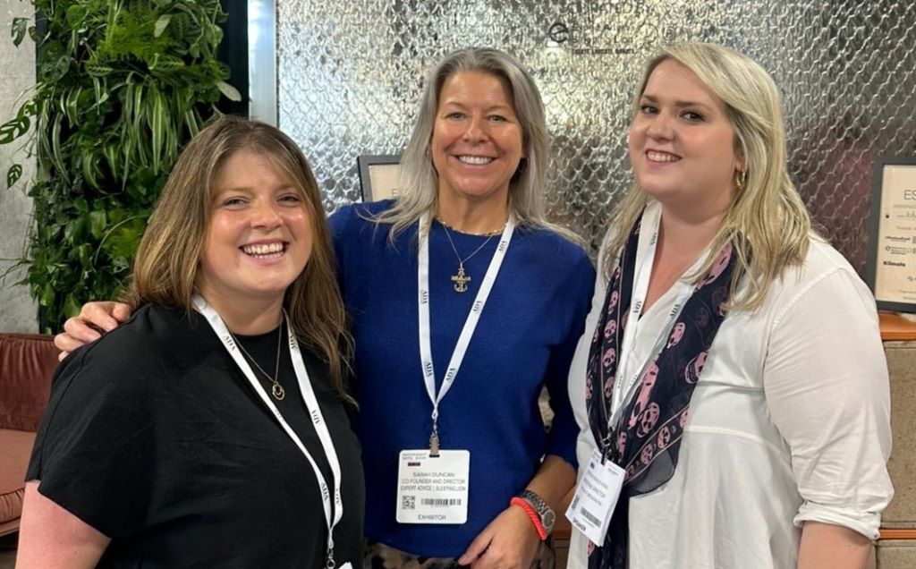 Three smiling women at a professional event.