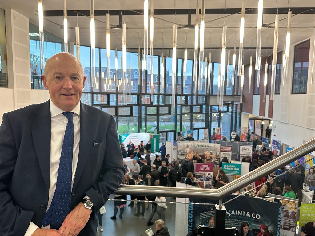 Businessman at busy indoor networking event with banners.
