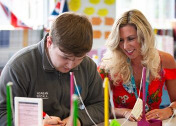 Teacher assisting student in classroom activity.