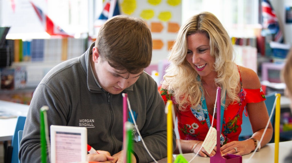 Teacher assisting student in classroom activity.