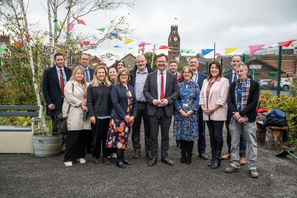 Group posing in community garden with colourful flags.