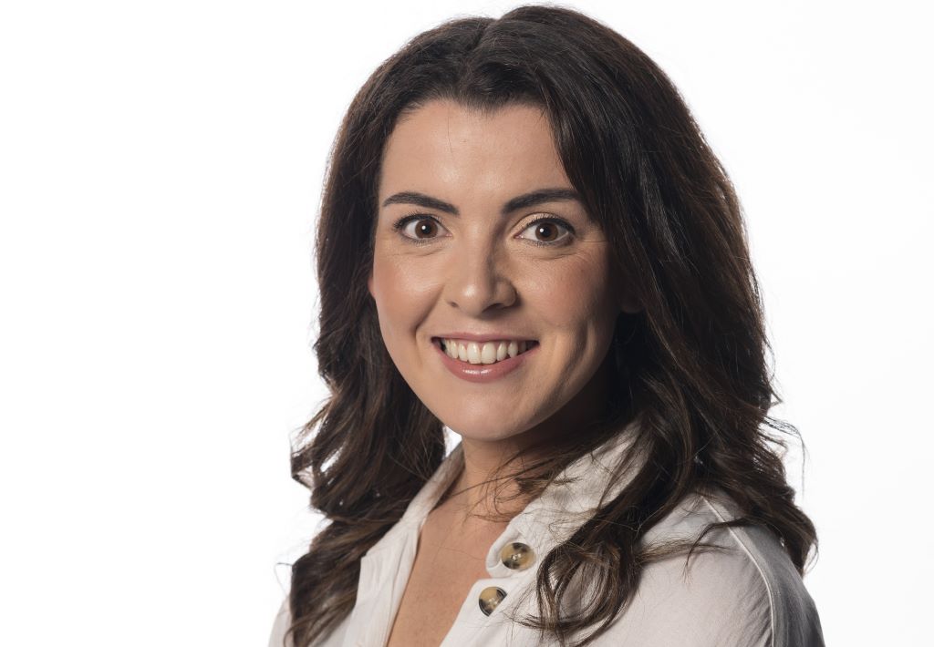 Smiling woman with dark hair in white shirt.