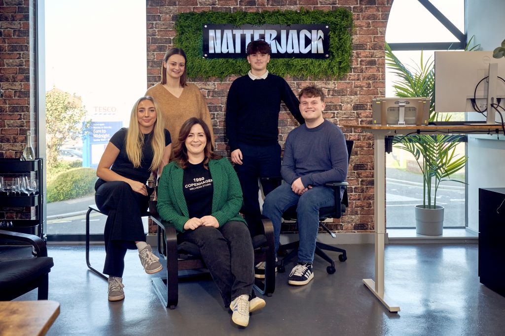 Five people posing in front of Natterjack sign.