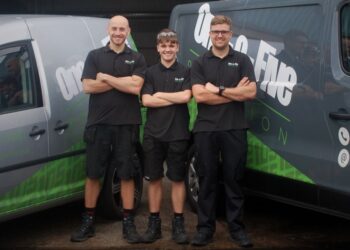 Three technicians standing by company vans.