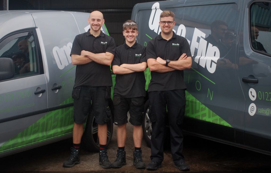Three technicians standing by company vans.