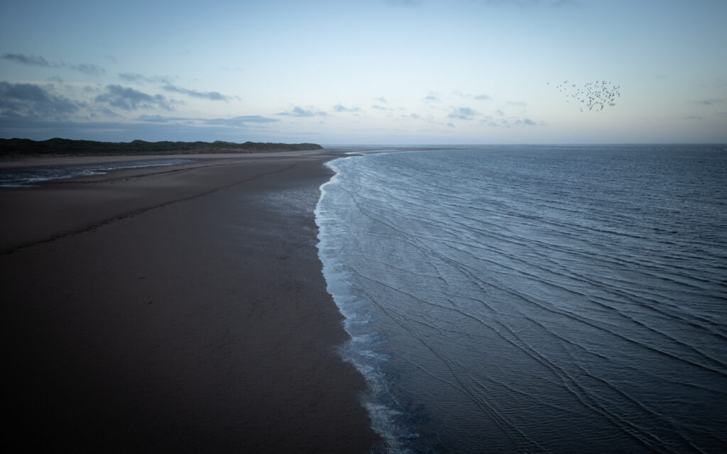 Coastal shoreline with gentle waves at dusk.