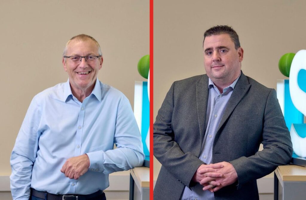 Two smiling men in business attire indoors.