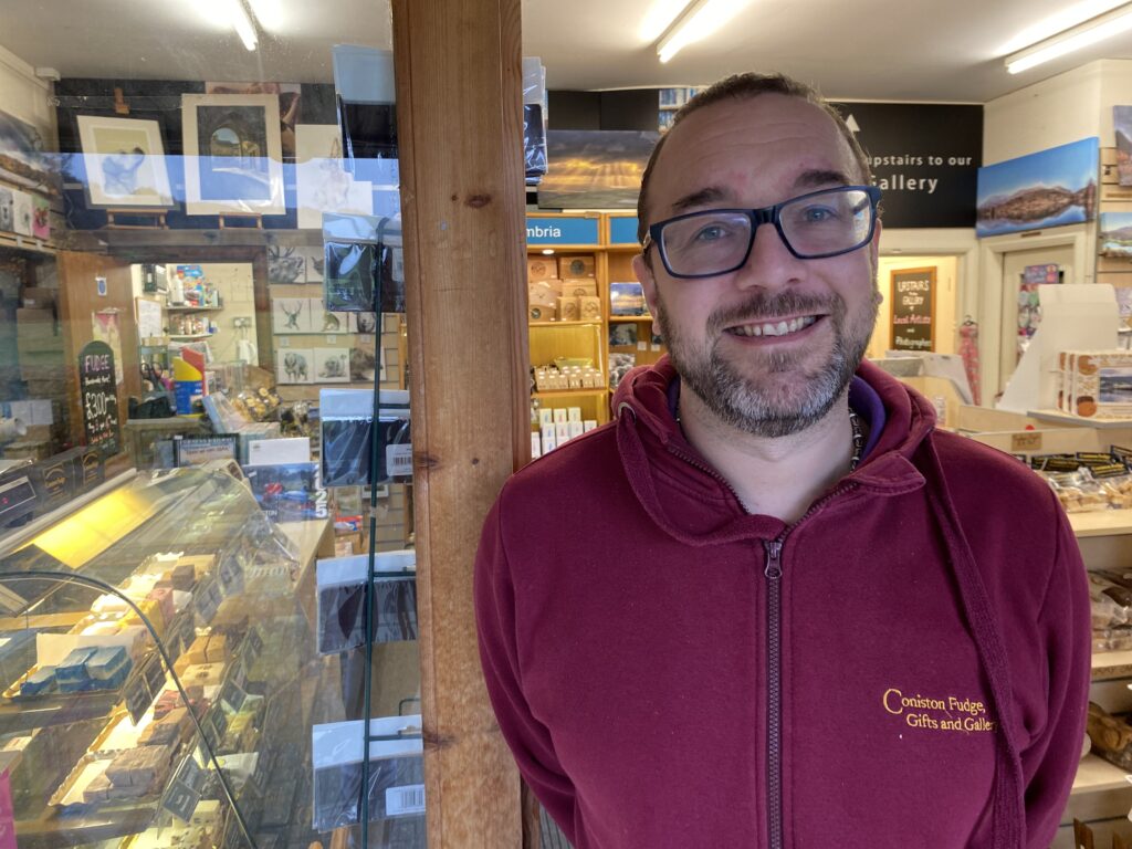 Smiling shopkeeper inside a gift shop.