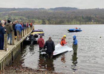 People at dock with powerboats on lake.